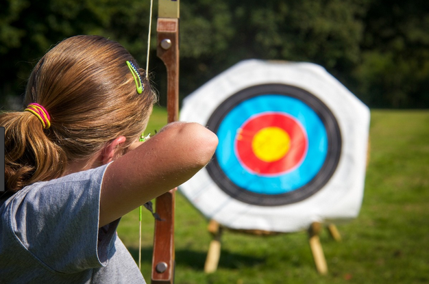 Archer woman aims her arrow at the target